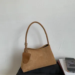 Minimalist brown suede underarm handbag with slim handle and matching shield tag