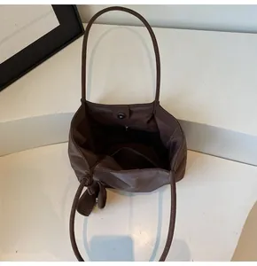 Detail of large brown tote bag showing magnetic buckle and interior pocket layout