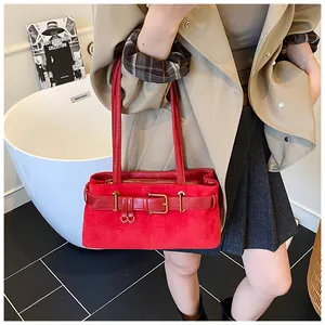 Mannequin portant un sac sous le bras en daim rouge avec boucle dorée sur un trench kaki
