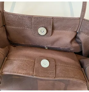 Detail of dark brown tote bag interior featuring magnetic closure and zippered pocket