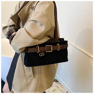 Détail d'un sac à bandoulière vintage en daim avec lanières en cuir marron et boucles dorées