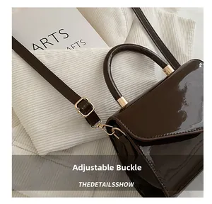 Détail de la boucle dorée réglable et de la bandoulière en cuir verni marron foncé brillant