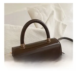Détail du sac à main en cuir verni marron foncé avec fini brillant et boucles dorées