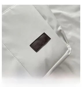 Détail d'un sac cabas en tissu blanc avec étiquette en cuir marron et logo mode