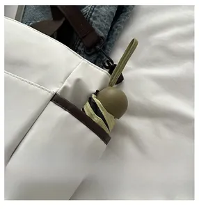 Gros plan d'une poche latérale de cabas blanc avec un mini parapluie à l'intérieur