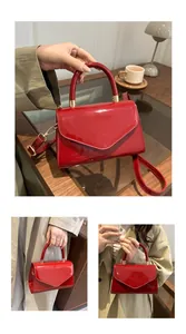 Détails du sac enveloppe en cuir verni rouge avec boucles dorées et bandoulière amovible