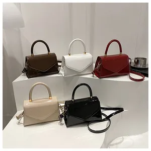 Détail de cinq mini sacs en similicuir brillant en diverses couleurs sur présentoir