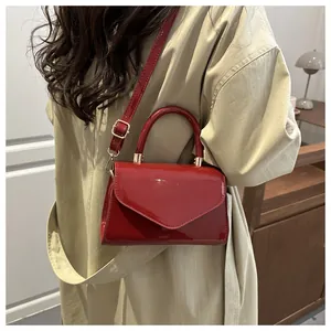 Détail du mini sac en cuir verni rouge avec boucles dorées et poignée supérieure