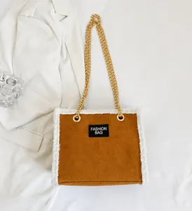 Nahaufnahme der braunen Veloursleder-Tasche mit weißem Plüschrand und goldener Kette