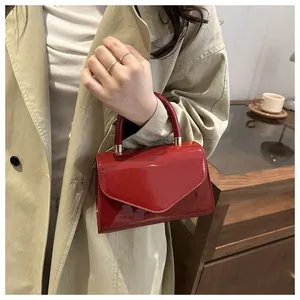Détail d'un mini sac à main rouge en cuir verni avec ferrures dorées et rabat enveloppe