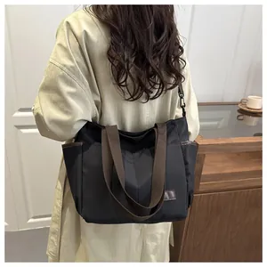 Détail du grand sac cabas noir avec bandoulières marron et poches latérales pratiques