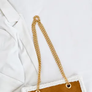 Detailansicht der goldener Kette an brauner Wildledertasche mit Plüschbesatz für Winter