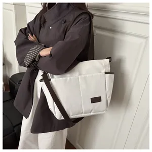 Détail du sac fourre-tout en toile blanche avec bandoulière brune et étiquette en cuir