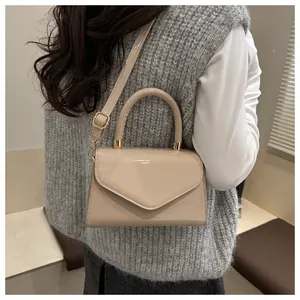Gros plan du petit sac beige verni avec finitions dorées et rabat de style enveloppe