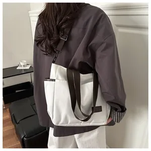 Vue arrière d'un sac cabas en toile blanche avec bandoulières marron sur tenue décontractée