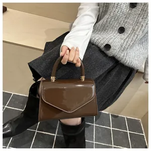 Détail d'un sac à main en cuir verni marron avec rabat triangulaire et finition brillante