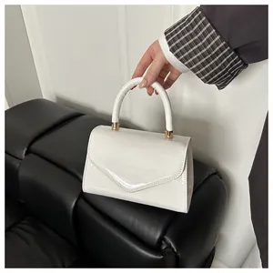 Détail d'un sac à main blanc en cuir verni avec rabat en V et finitions en métal doré