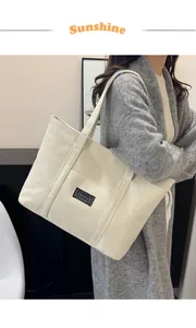 Dettaglio della borsa tote in tela bianca con etichetta nera e doppi manici resistenti