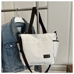 Vue détaillée du sac cabas crème avec sangles marron et poches latérales fonctionnelles