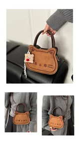 Detail of a brown cat-shaped bag with suede finish and colorful clown plush charm