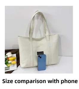 Dettaglio della borsa tote in tela con confronto dimensioni con uno smartphone