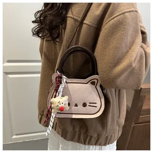 Detailed view of pink cat-shaped handbag featuring whiskers and plush biscuit charm