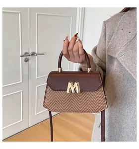 Detail of retro shoulder bag featuring two-tone leather, woven texture, and gold M buckle