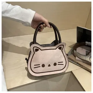 Detail of pink cat-shaped crossbody bag featuring fine embroidery and brown leather handles