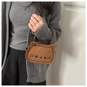 Detail of cute cat shaped brown handbag showing embroidery and soft suede texture
