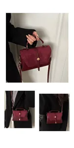Detail view of burgundy leather handbag showing golden metal lock and chic styling