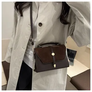 Dark brown leather handbag shown crossbody style on a model in a minimalist setting