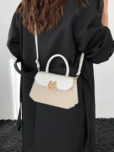 Retro cream white patchwork crossbody bag with gold M logo on a trench coat model