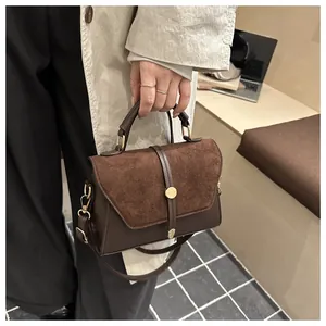 Detail of dark brown leather handbag featuring matte flap and gold round buckle