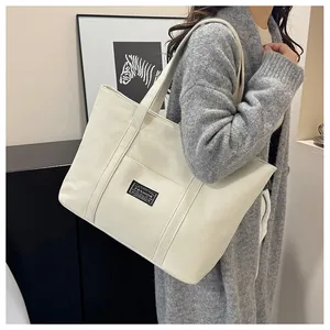 Dettaglio della grande borsa tote in tela beige con etichetta fashion e cinghie verticali