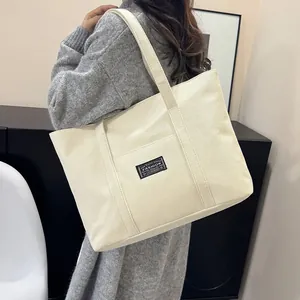 Dettaglio della grande borsa tote in tela crema con toppa Fashion nera e manici