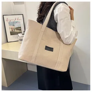 Dettaglio di una borsa tote in lino beige con toppa FASHION nera e ampi spallacci comodi