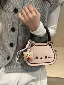 Pink cat-shaped plush handbag with brown handles and cookie charm in a lifestyle setting