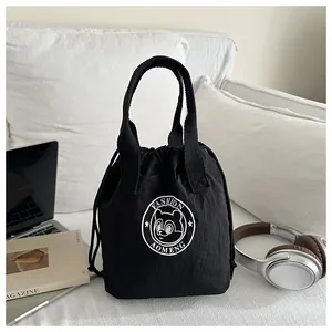 Detail of waterproof black drawstring bucket bag with bear logo on a white sofa