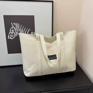 Dettaglio della borsa tote in tela bianco crema con etichetta tessuta nera FASHION