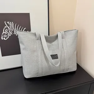 Dettaglio della trama in lino spesso di una grande borsa tote grigio chiaro con etichetta