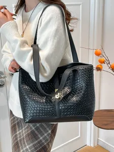 Minimalist black woven tote bag with magnetic clasp and contrast stitching on the shoulder strap