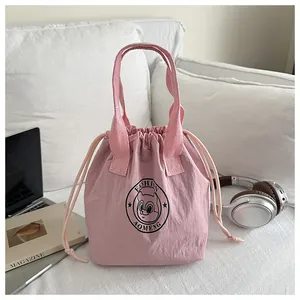 Pink drawstring thermal lunch bag with squirrel logo on a stylish white sofa setting