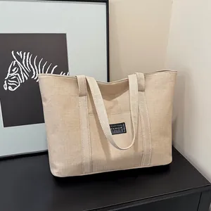 Dettaglio della borsa tote in lino e cotone beige con trama in tela e toppa logo