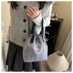 Close-up of gray waterproof lunch bag with navy handles and cute bear logo detail