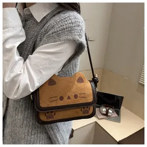 Detail of cute cat-shaped crossbody bag featuring plush khaki fabric and brown leather trim