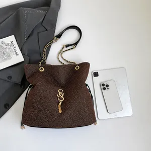 Detailed macro view of the brown grained leather handbag with gold S logo and fringe