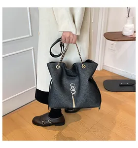 Detailansicht der schwarzen Schultertasche mit goldener Kette und modischem Quastenanhänger
