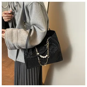 Detail of black leopard print tote bag featuring decorative pearl and floral metal chain