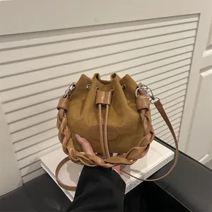 Sac seau en daim marron avec poignée tressée et bandoulière longue réglable