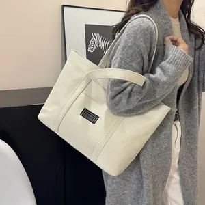 Grande borsa tote in tela bianco sporco con etichetta moda indossata da una modella